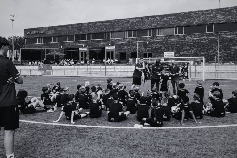 Jeugdvoetbaltraining op het veld van Voetbalschool Groesbeek met jonge spelers en instructeurs tijdens de zomerse actie.